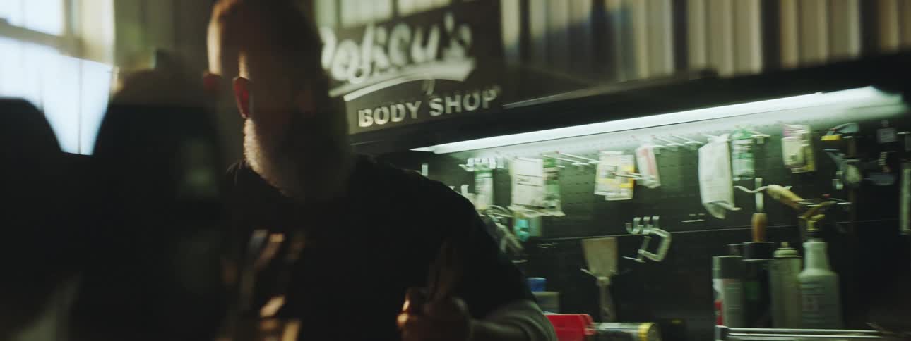 Man with beard and shaved head working in an auto body parts shop moving quickly