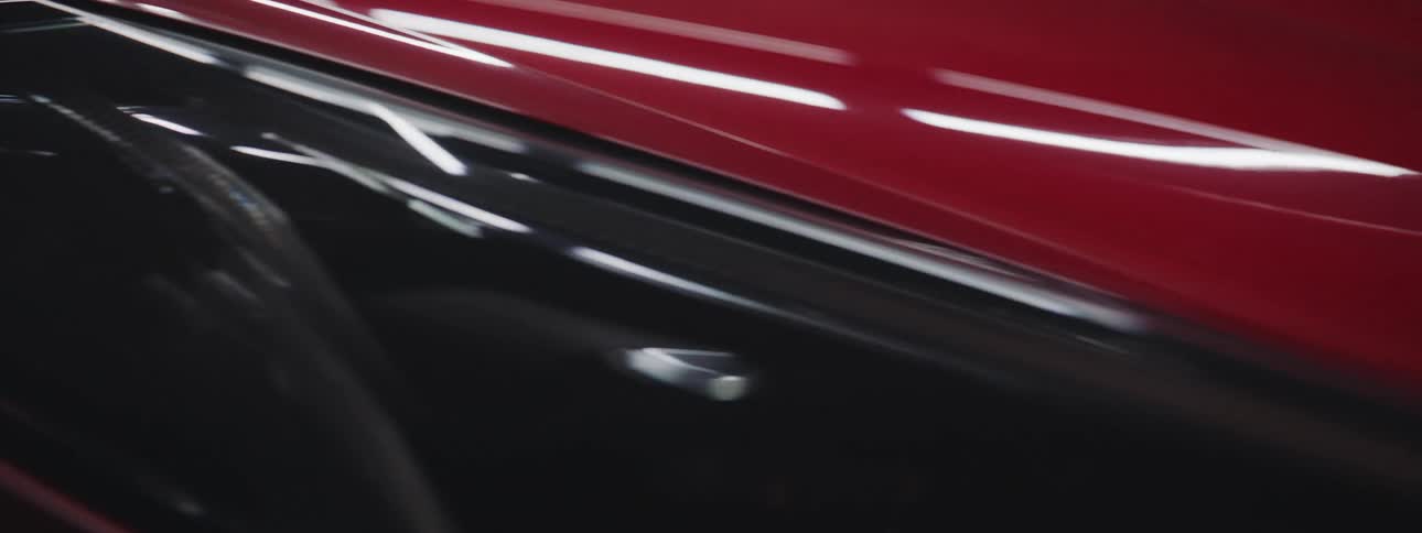 A close up of a red car fender with light reflecting off it