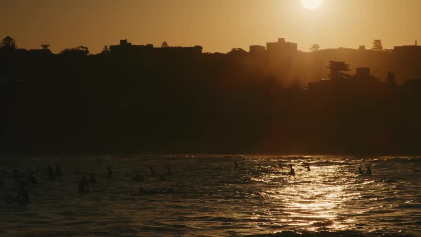 The sun is rising on the surfers