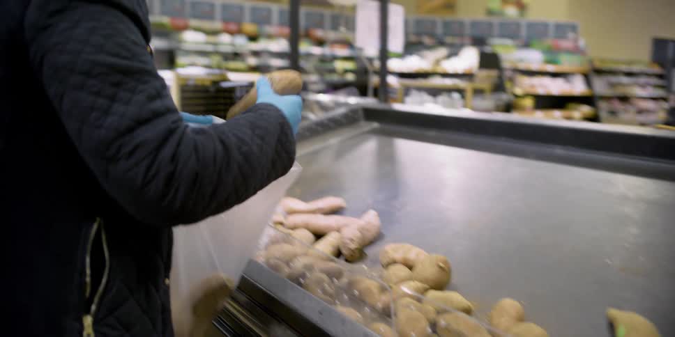 A customer chooses and bags potatoes at a grocery store