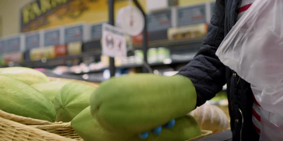 Woman wearing mask and latex gloves buying groceries in supermarket