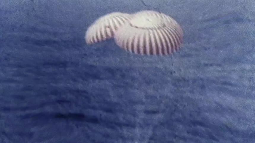 Distorted footage of a space capsule splashing down in the ocean caught on vintage film