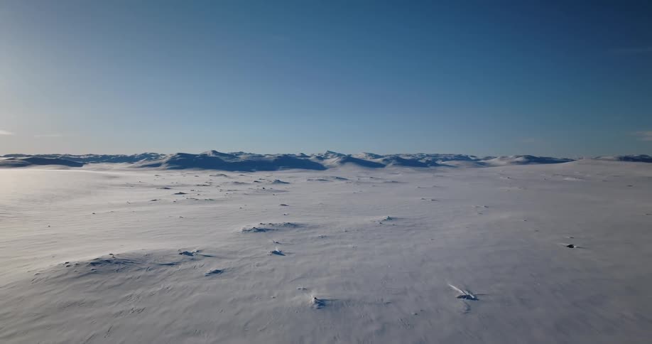 An aerial view of snow covered grounds with mountains in the distance