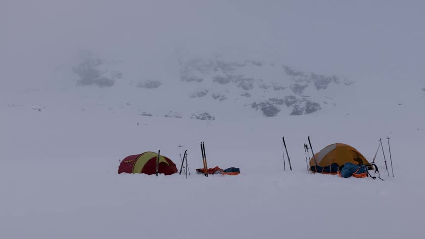 Mountain tents assembled over the snowy landscape under the mist