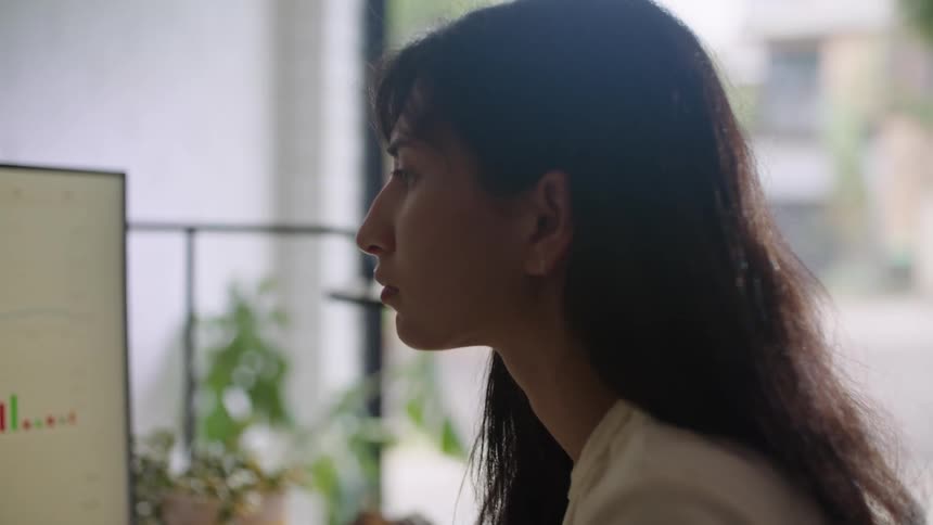 A young woman is in the office and is using her computer