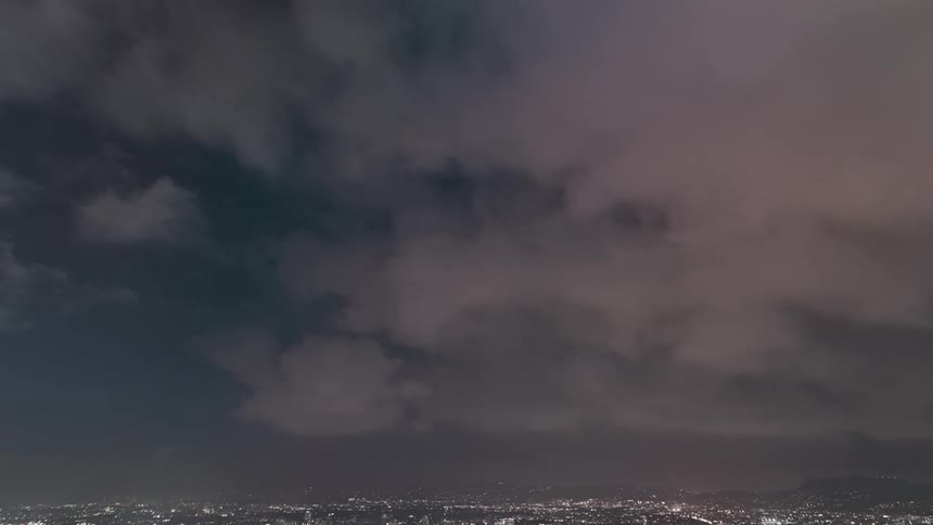 Clouds move over town as the sky grows dark and lights on buildings glow