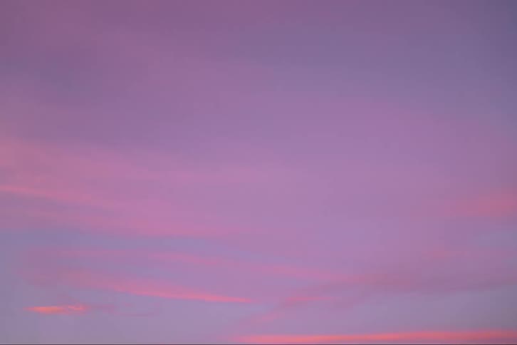 Thick clouds move across the sky as the sun sets and the sky turns pink and lavender