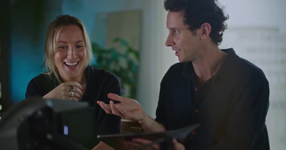 Two people on a room have a lively conversation while configuring a drone over a table