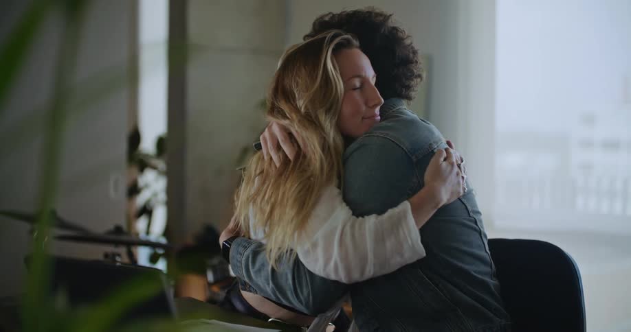 Couple hug and smile in middle of discussing laptop contents