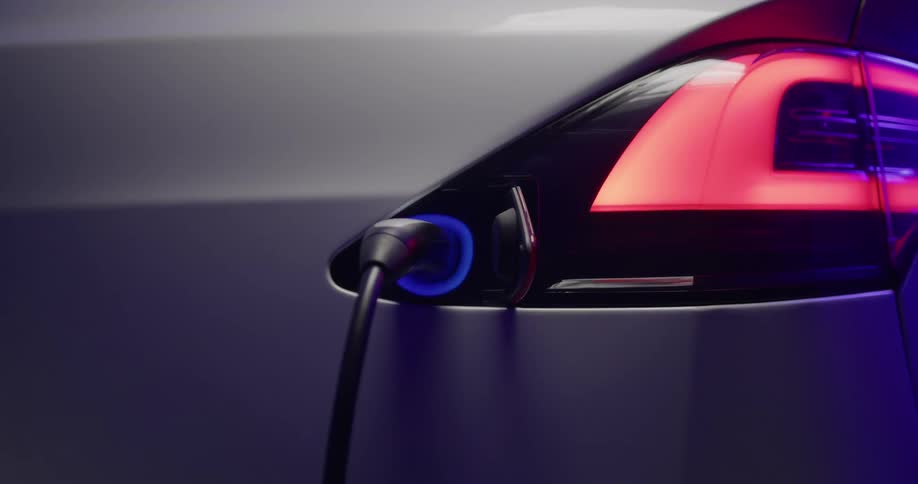 The view is of a car and someone plugging in a cable to charge it