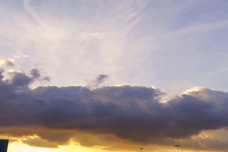 A time lapse of clouds rolling across the blue then orange hue sky