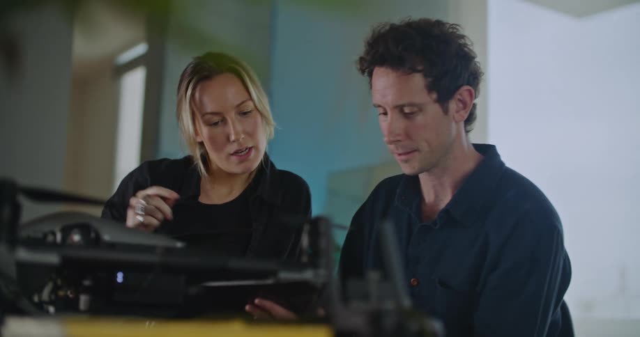 A couple programs a drone using a tablet indoors