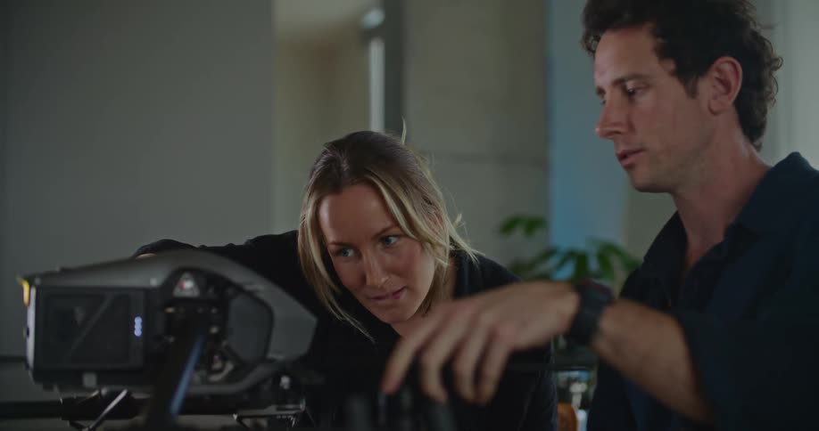 A woman and a man working indoors configure a drone over a table