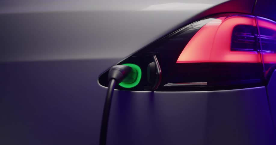 Charging cable plugged into electric car as it changes from blue to flashing green and charges