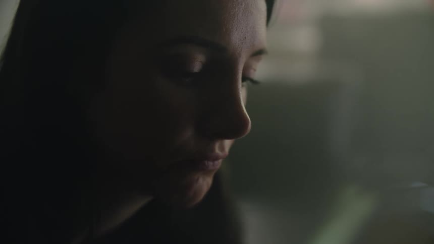 A female is sitting indoors by herself in a room