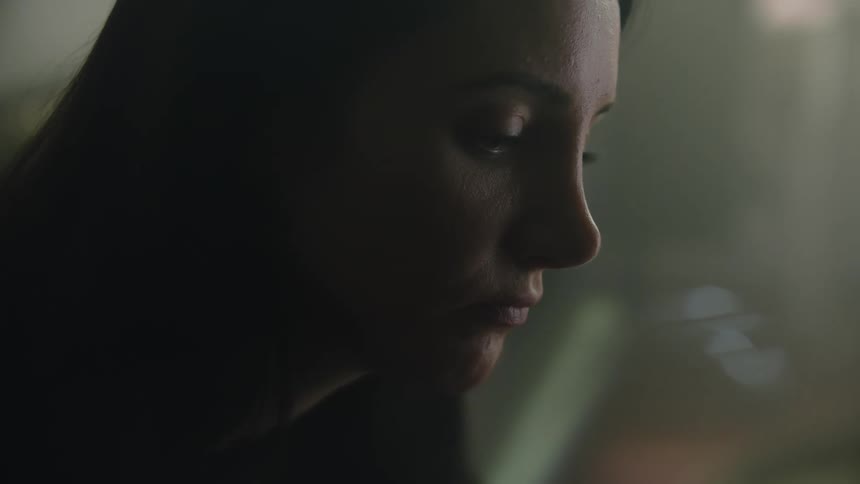A woman is sitting in a room by herself and looks sad