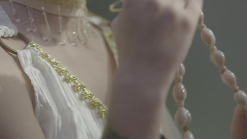 A person wraps a shell necklace around her hands