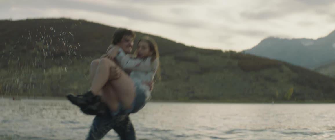 A man picks a woman up and dunks her into the water