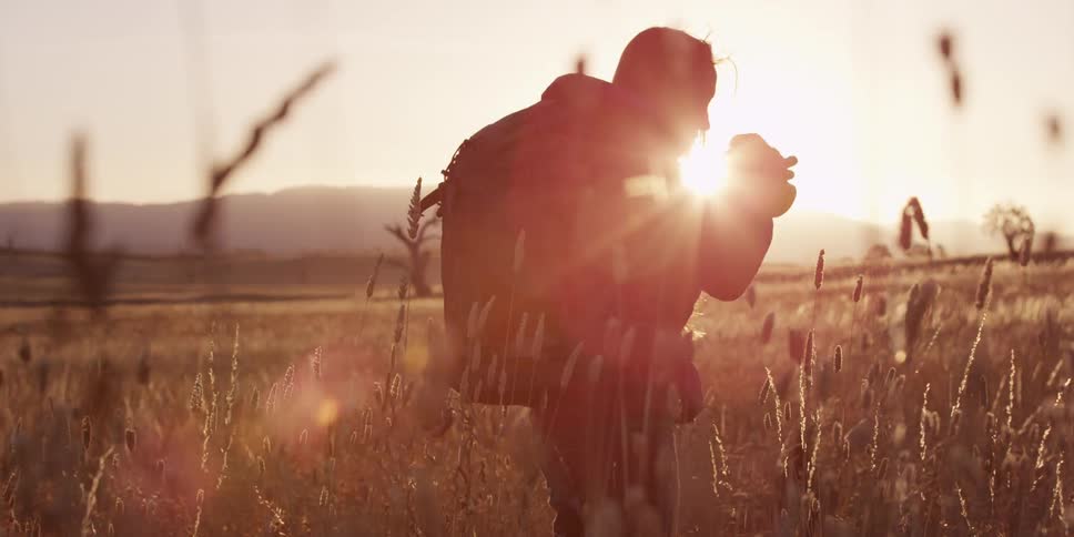 A photographer is taking pictures in a field at sunset