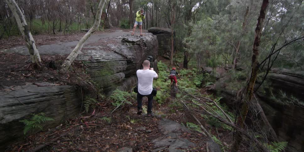 A man is chasing after a mountain biker with a camera