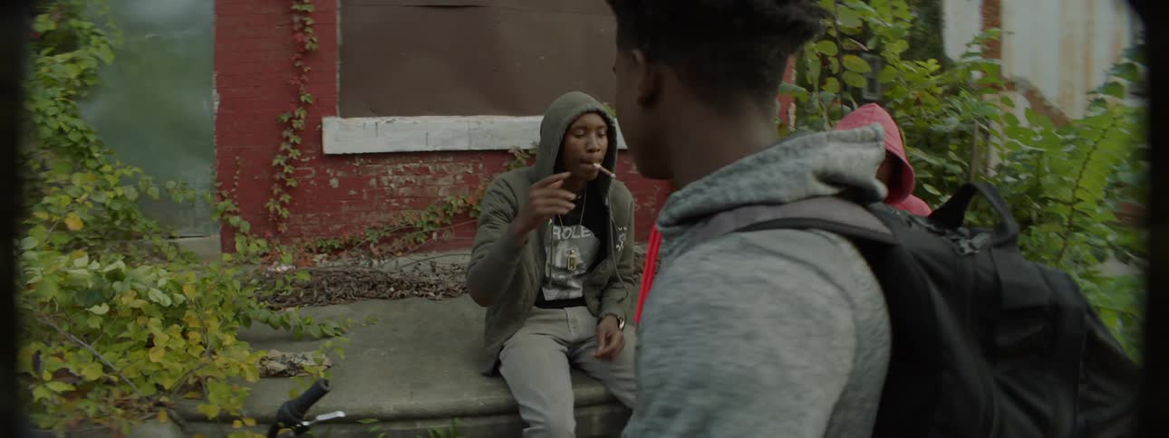 A young man shakes hands with his friends and walks away
