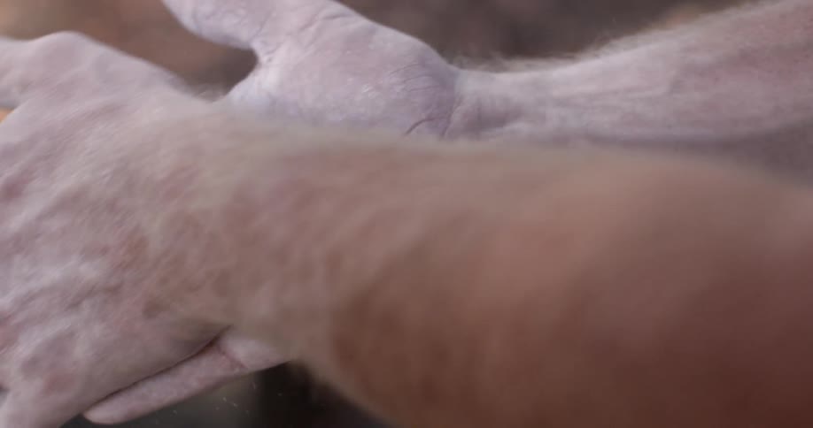 A man taking chalk out of a bag and rubbing it all over his hands