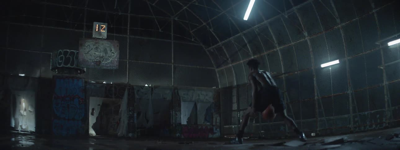 A man is dribbling a basketball on a court at night