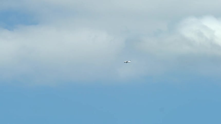 Plane flies through a partly cloudy sky