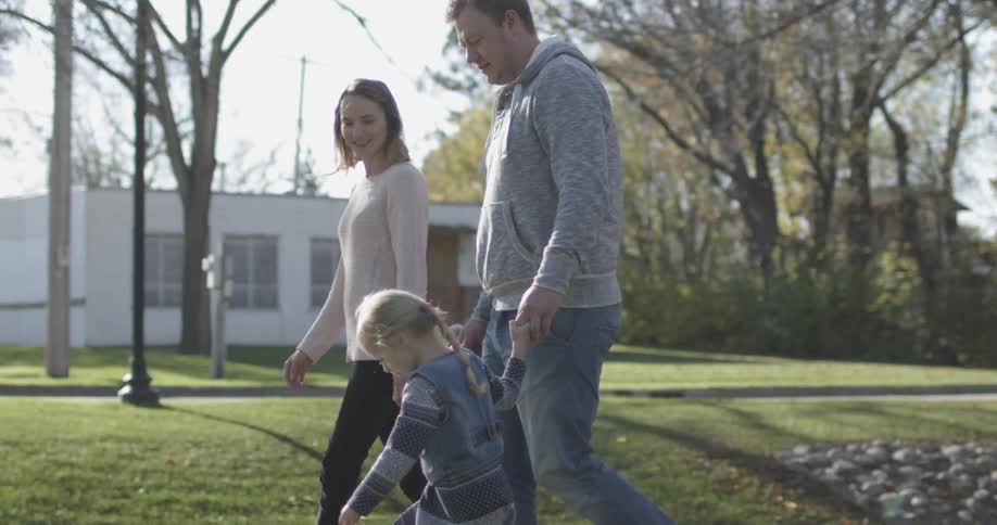 A man and woman walk children down a sidewalk