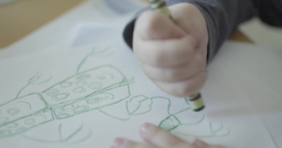 A child draws a picture in green crayon