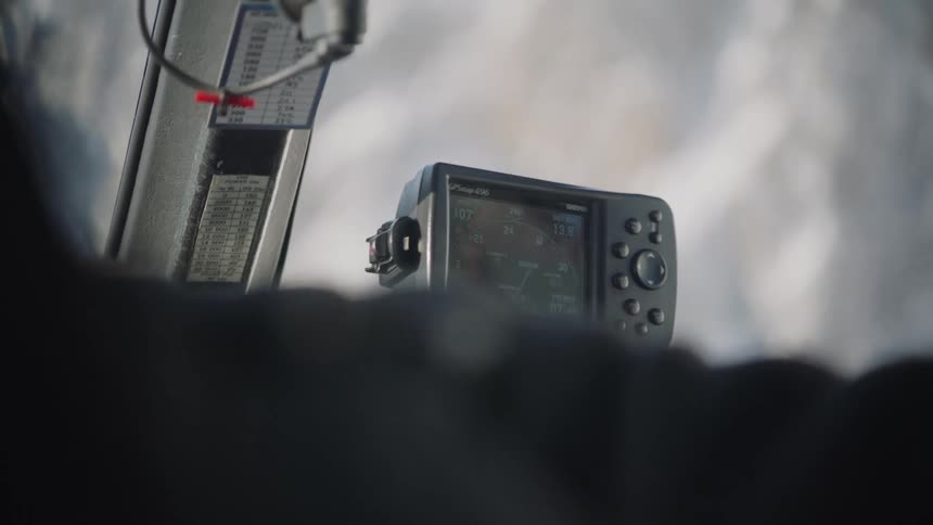 An up close of a person motioning with their hands while a small electronic device sits on the dashboard