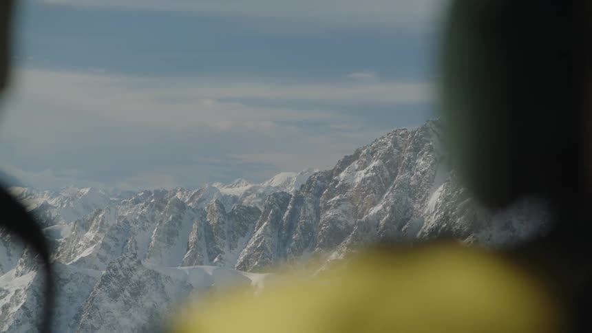 Pilot flies over snow covered mountain range on cloudy day