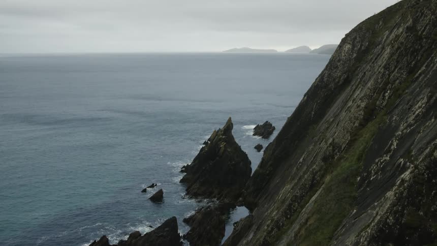 Rock promontory in front of a cliff next to the ocean at daytime