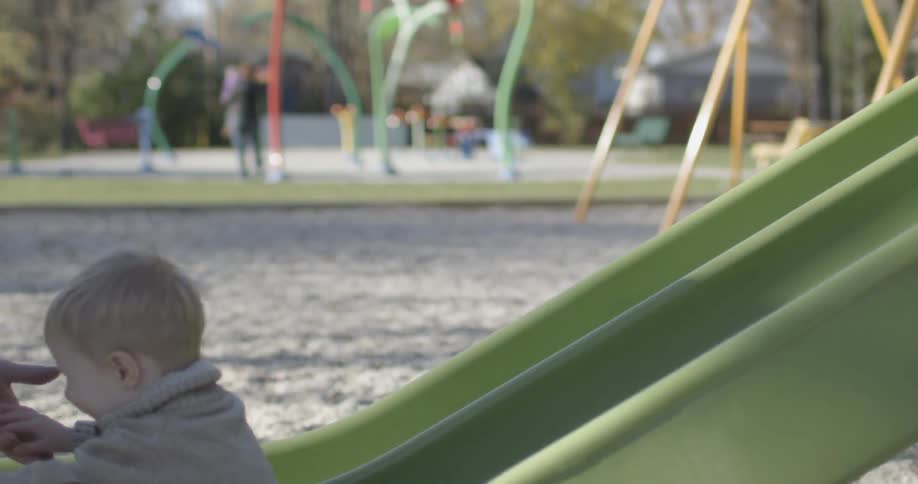 A little boy going down a slide