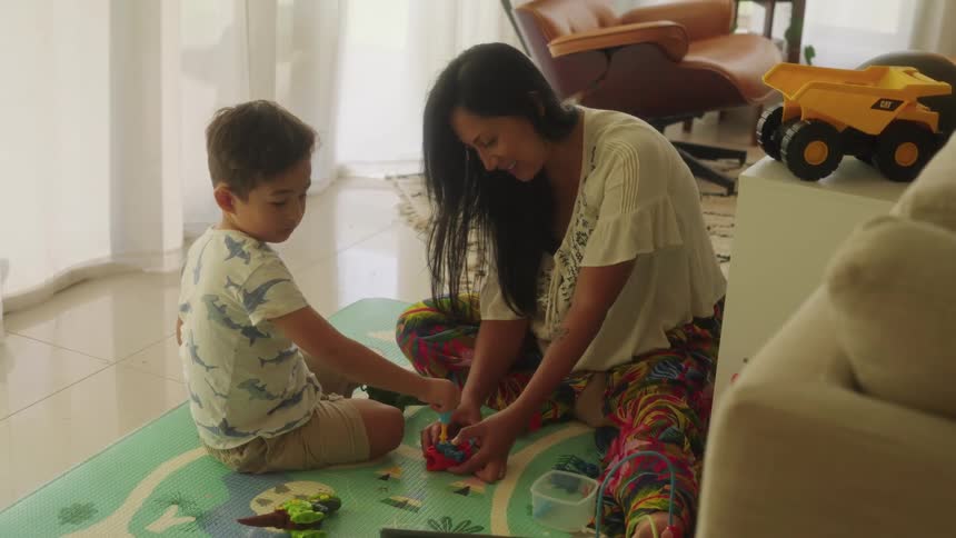A mother and son play with toys on the ground