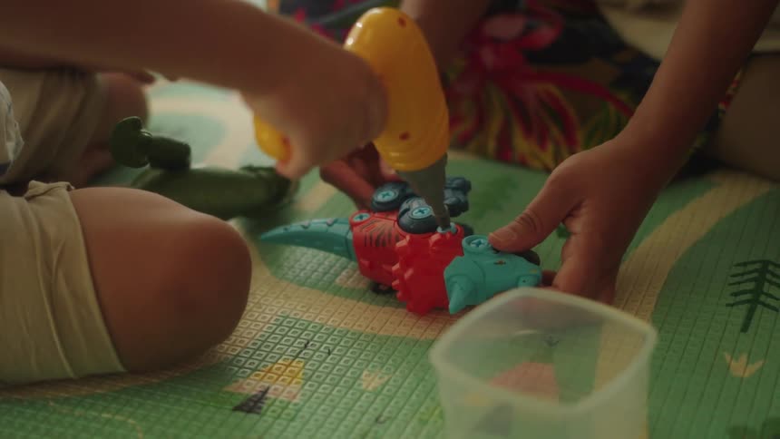 Mother sits on the living room floor with her son to play with toys