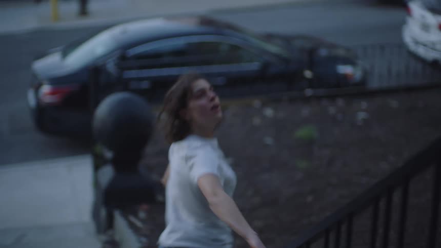A woman running out of her house frantically looking at the house and then running into the street