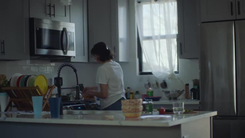 A woman makes something in the kitchen