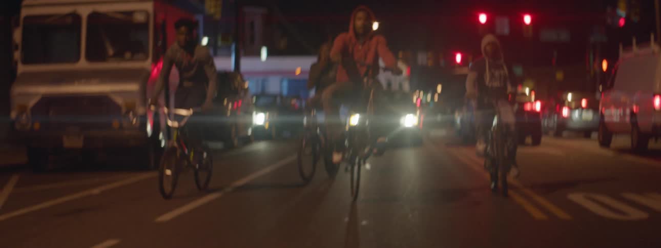 A busy street has bikes and cars riding at night