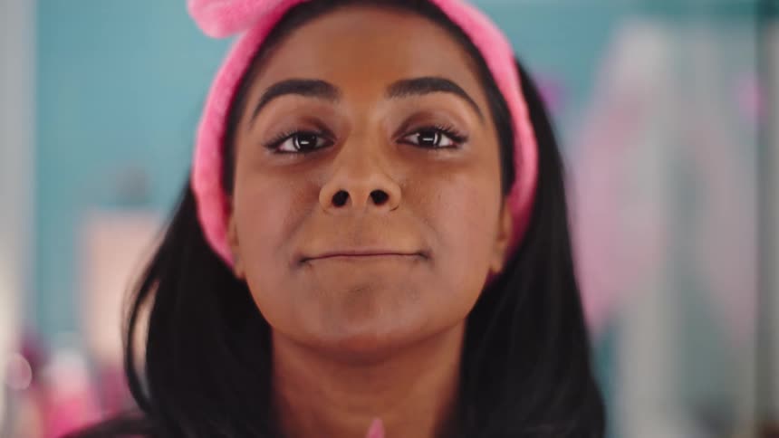 A female is applying makeup while looking in the mirror