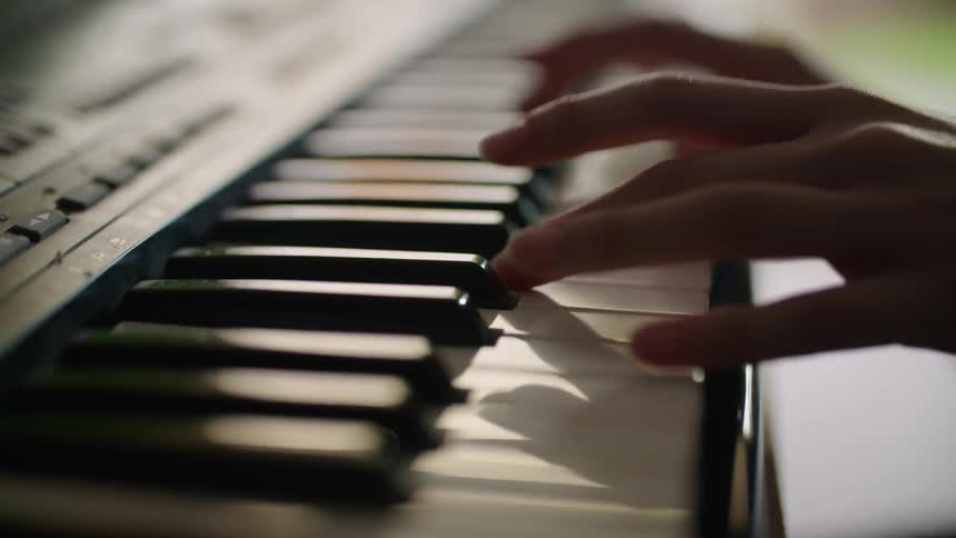 Two hands play a piano keyboard