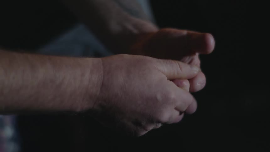 A man is touching his hands together while sitting