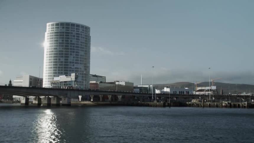 Cars moving on a bridge over a wide body of water near a high-rise