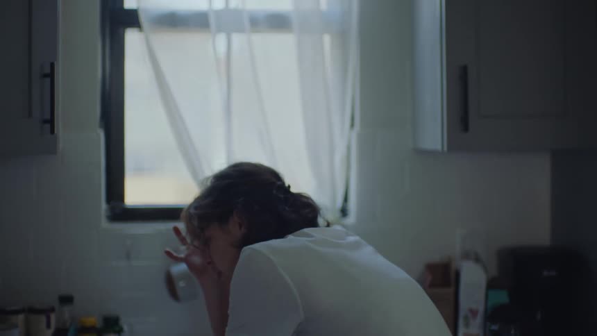 Young woman standing on the kitchen at home tries to control herself while suffering a panic attack