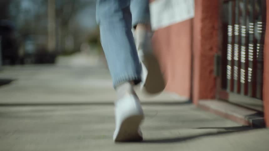Person runs along sidewalk past walls and fences in neighborhood
