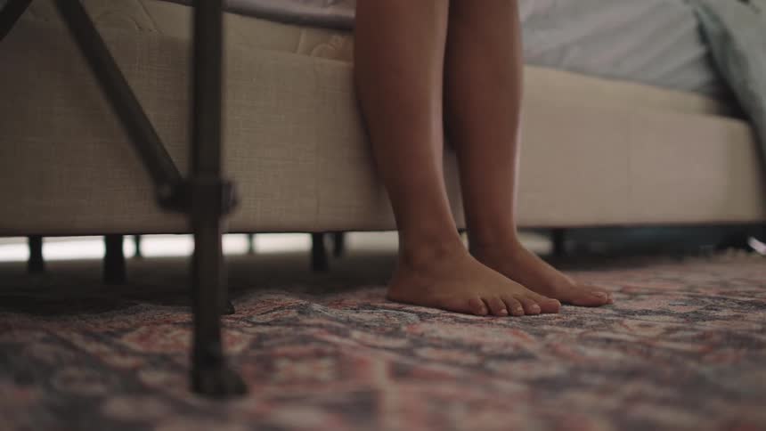 Close up of the bare feet of a person getting out of bed at home