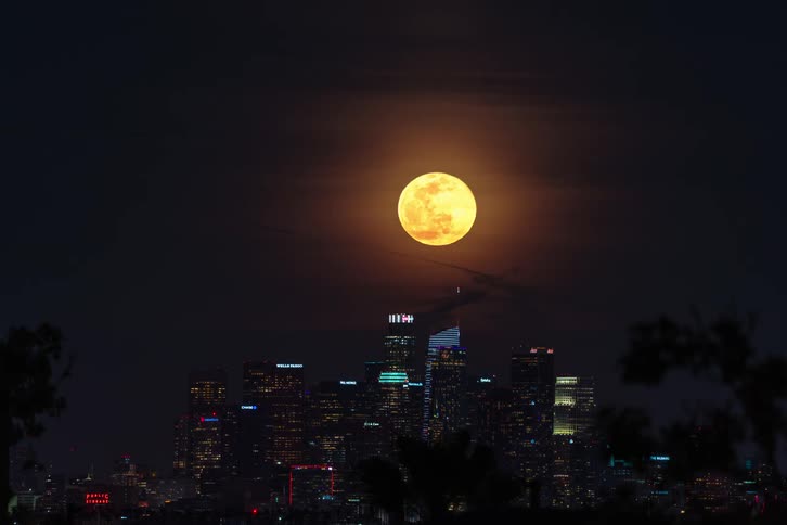 Time lapse view of the moon rising in the sky above the city