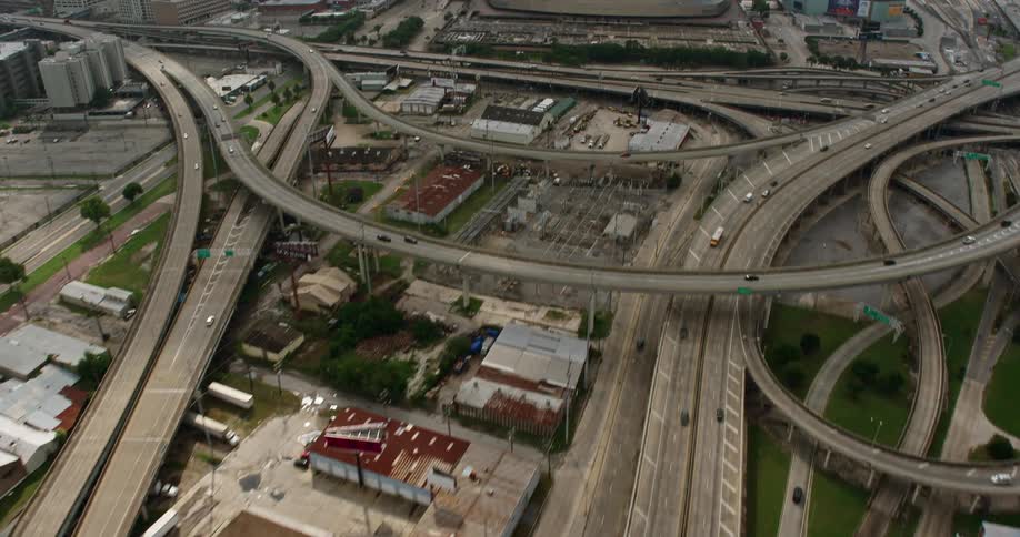 A cinematic aerial view of New Orleans Louisianas freeway interchange and Superdome showcasing the bustling metropolis and sports arenas during the daytime