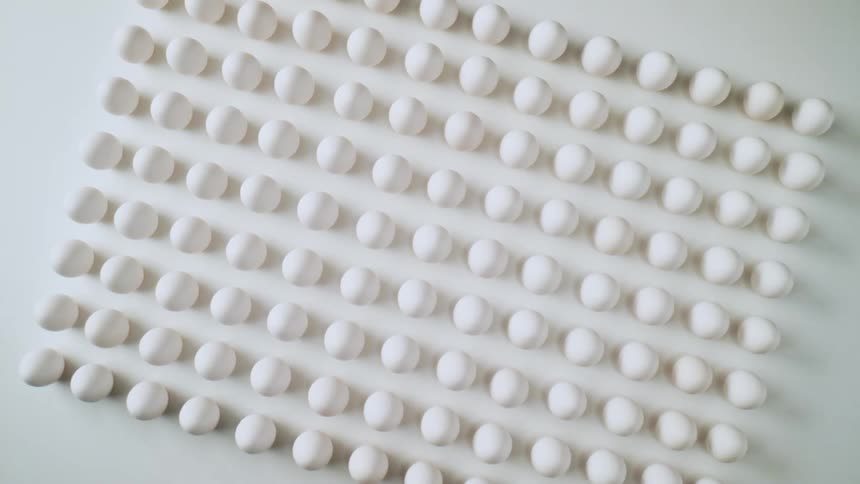 White spheres cast small shadows while lined up in rows and columns to form rectangular shape