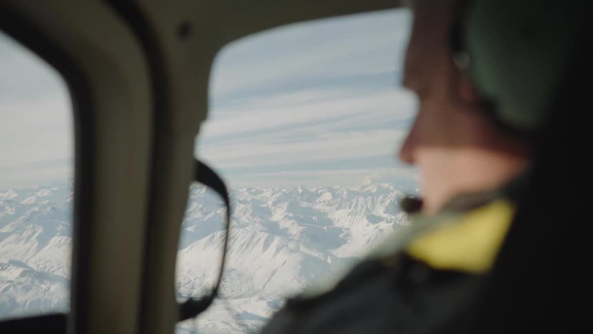 Aircraft pilot talks via headset while flying over snow covered mountains